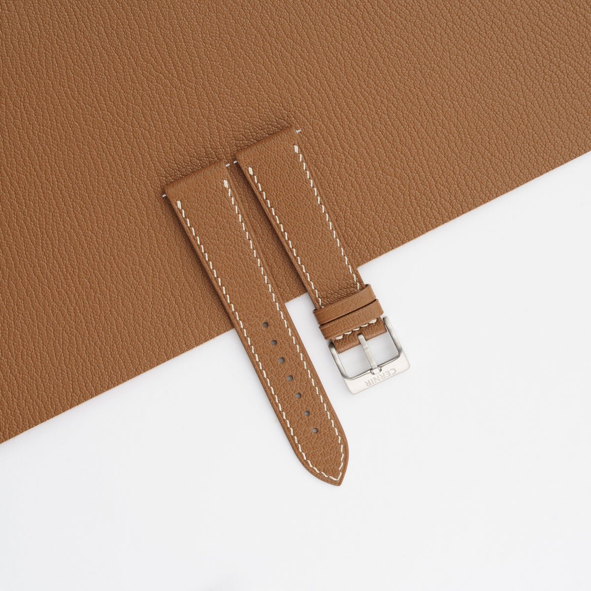 Golden brown Alran Chevre Sully goatskin slim watch strap with cream stitching, laid on a matching goatskin sheet with a fine grain