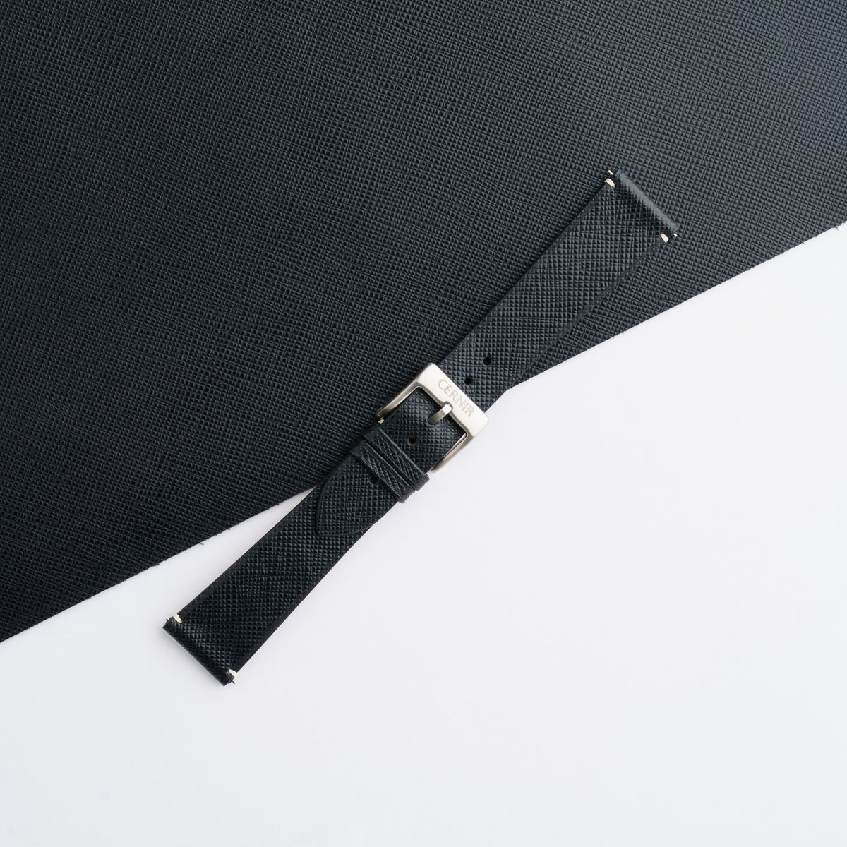 Black Saffiano side-stitch strap buckled, showing the crosshatch grain and plain unstitched edges