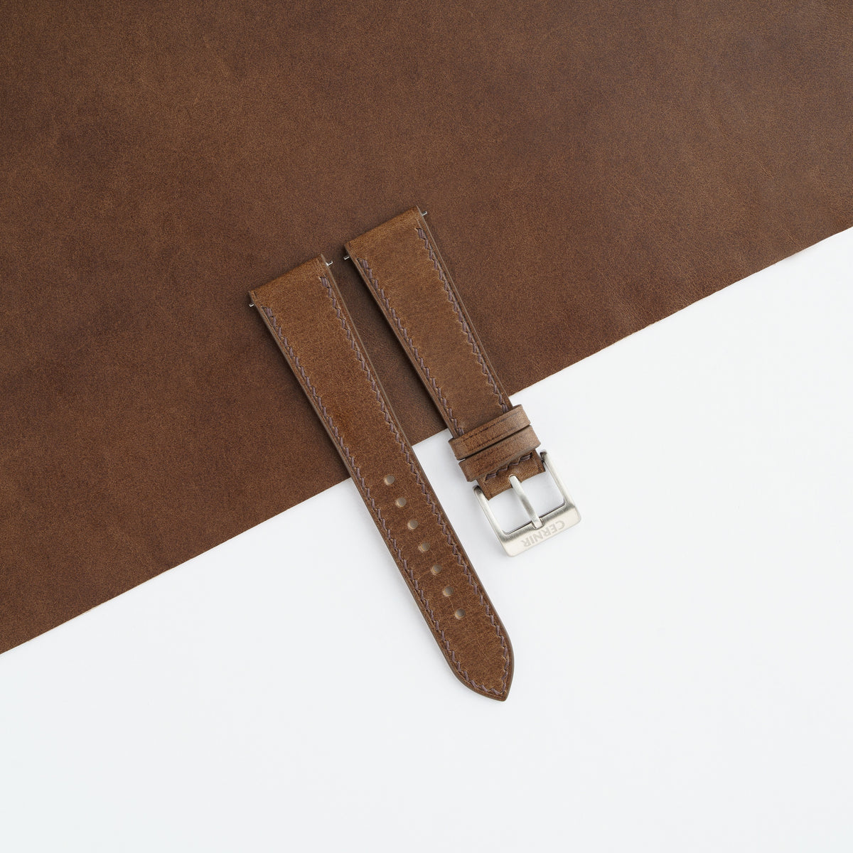 Brown Buttero slim watch strap laid on a sheet of matching brown leather