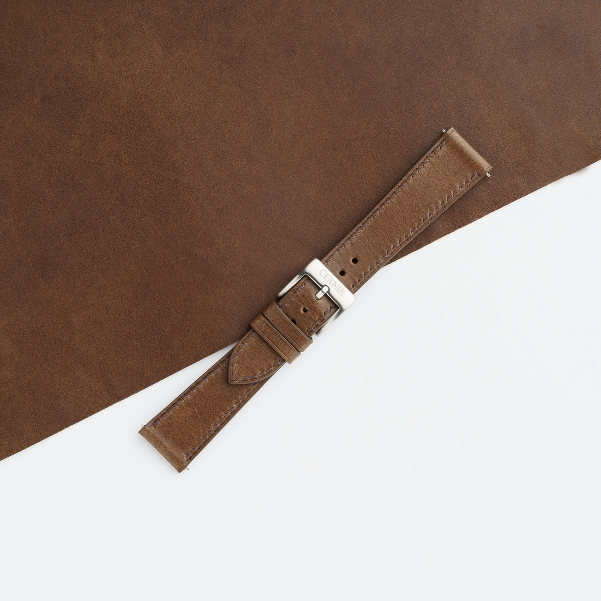 Brown Buttero slim watch strap buckled with a steel pin buckle, showing its mottled surface