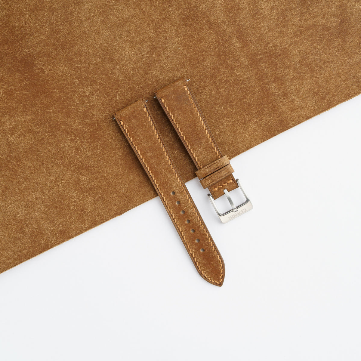 Cognac Pueblo leather slim watch strap laid on a sheet of matching Pueblo leather