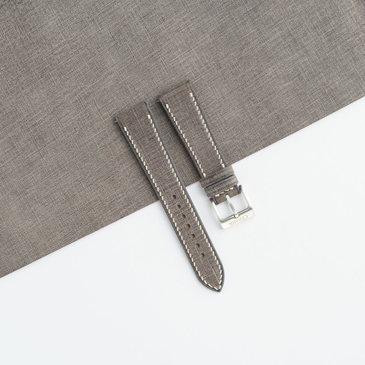 Grey Babele slim watch strap laid on a sheet of matching grey leather