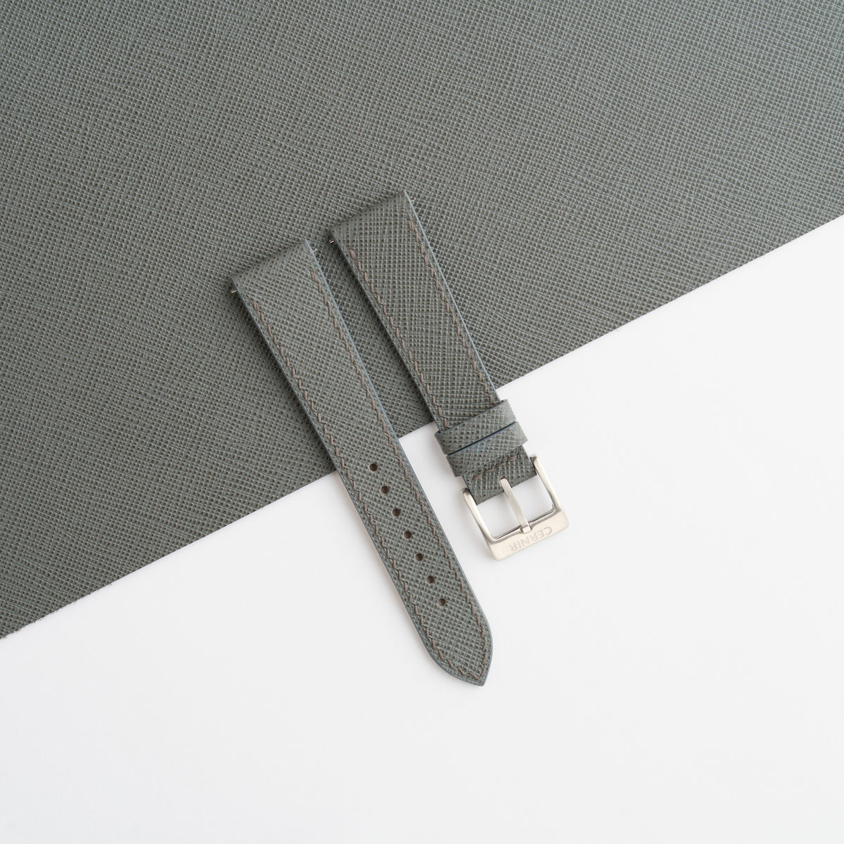 Grey Saffiano slim watch strap laid on a sheet of matching grey Saffiano leather