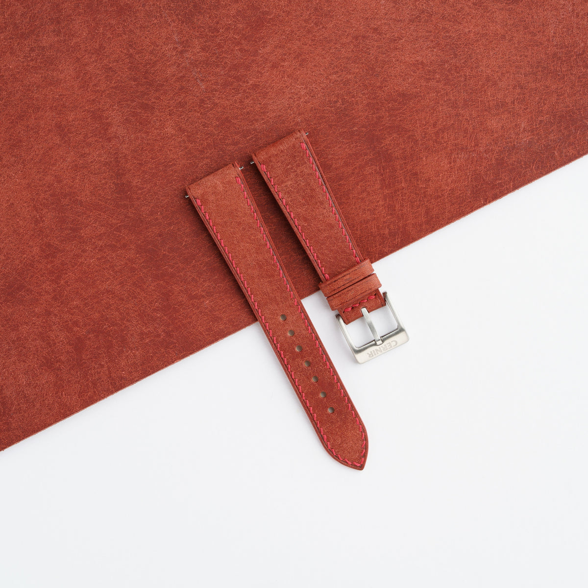 Rust brown Pueblo slim watch strap laid on a sheet of matching rust brown leather