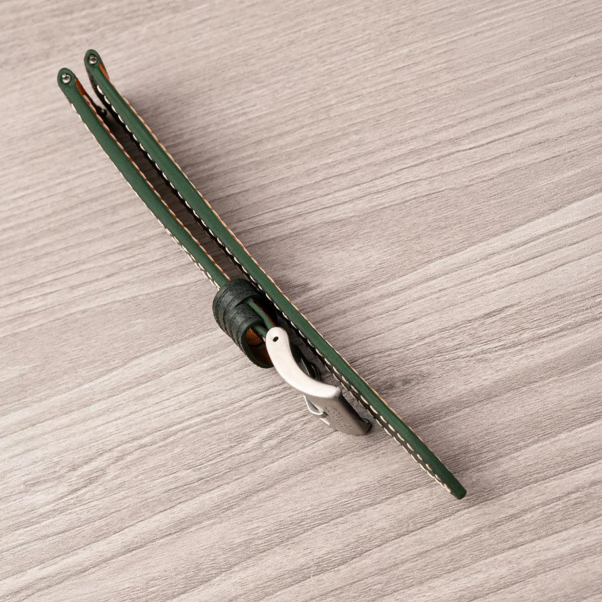 Side view of the forest green Saffiano slim curved end strap, showing its thin profile and painted edge