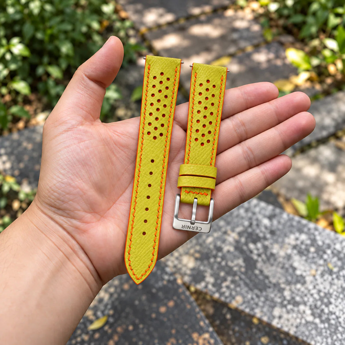 Lemon Yellow Epsom Racing Rally strap with orange stitching held in the hand, with a silver Cernir buckle
