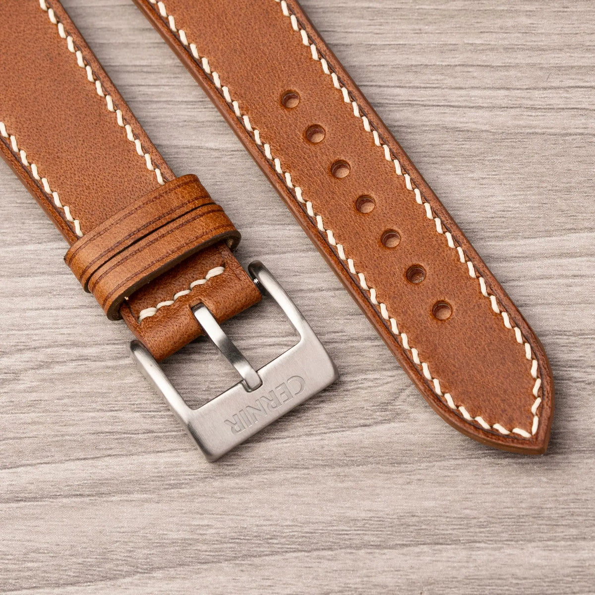 Close-up of the smooth Buttero leather, cream hand stitching and Cernir steel buckle on the tan strap
