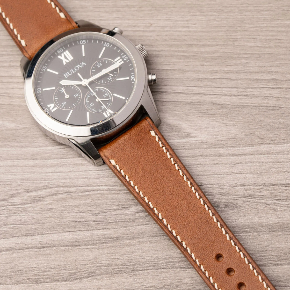 Tan Buttero curved end strap with cream stitching on a Bulova chronograph with a black dial