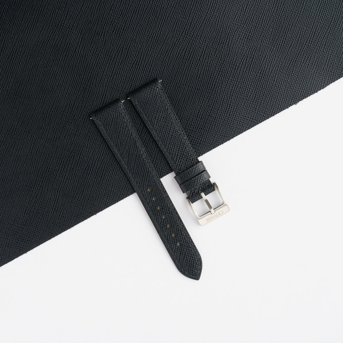 Black Saffiano slim watch strap laid on a sheet of matching black Saffiano leather
