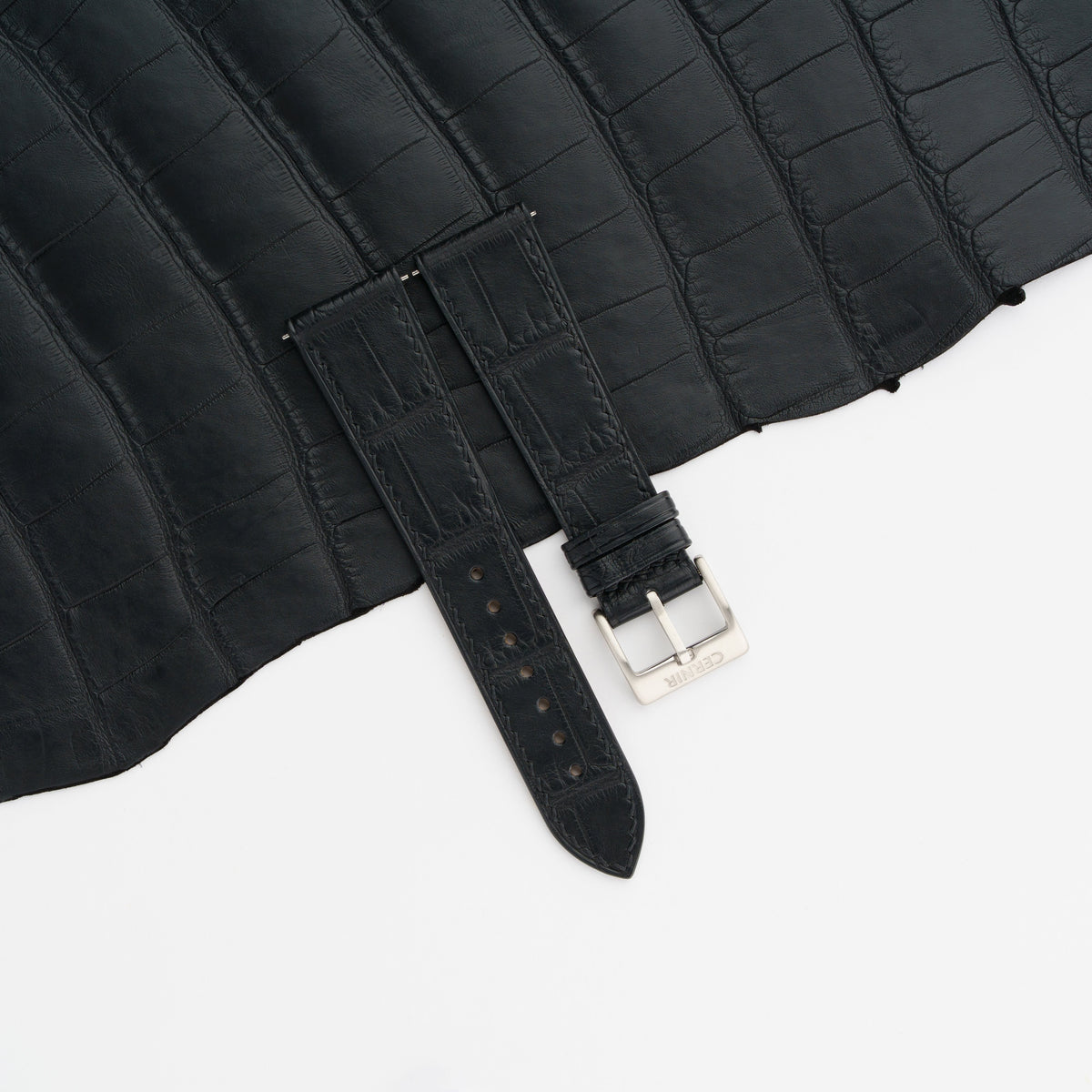 Black alligator slim watch strap laid on a black alligator skin