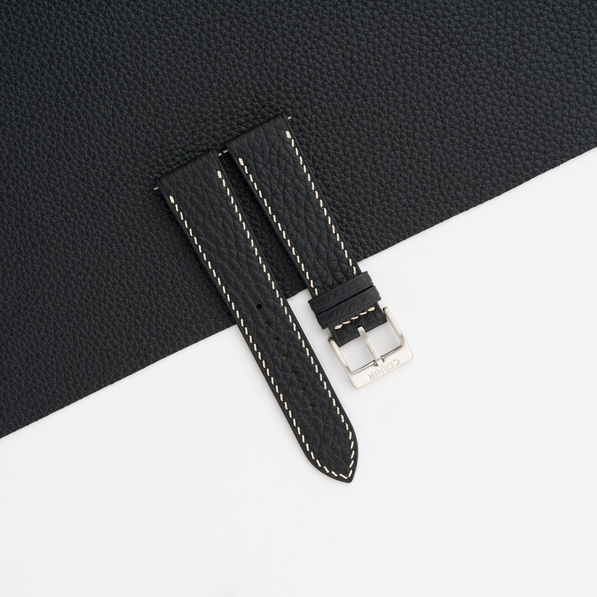 Black Togo slim watch strap with cream stitching laid on a sheet of matching black leather