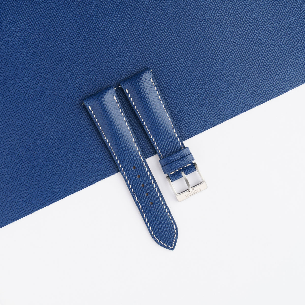 Blue Saffiano padded watch strap laid on a sheet of matching blue Saffiano leather