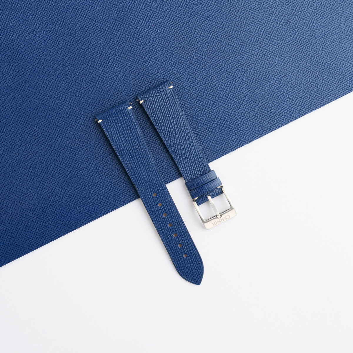 Blue Saffiano side-stitch watch strap laid on a sheet of matching blue leather