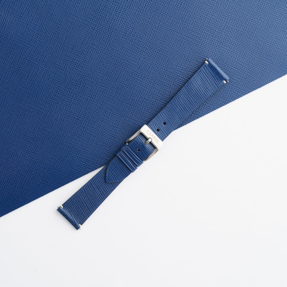 Blue Saffiano side-stitch strap buckled on matching leather, showing the crosshatch grain