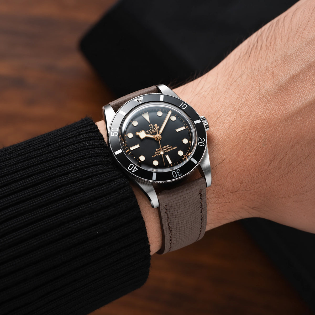 Brown sailcloth padded watch strap worn with a Tudor dive watch with a black dial