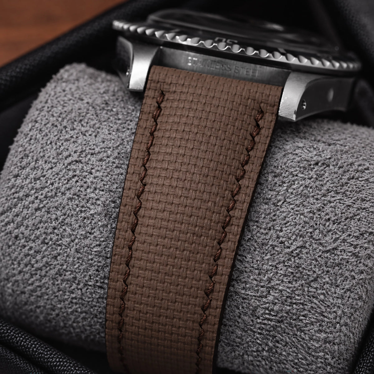 Side view of the brown sailcloth padded strap on a steel diver on a watch cushion