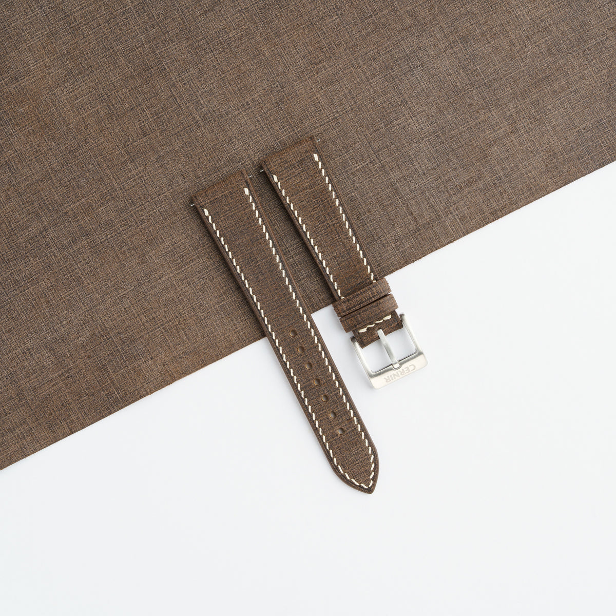 Dark brown Babele slim watch strap laid on a sheet of matching dark brown leather