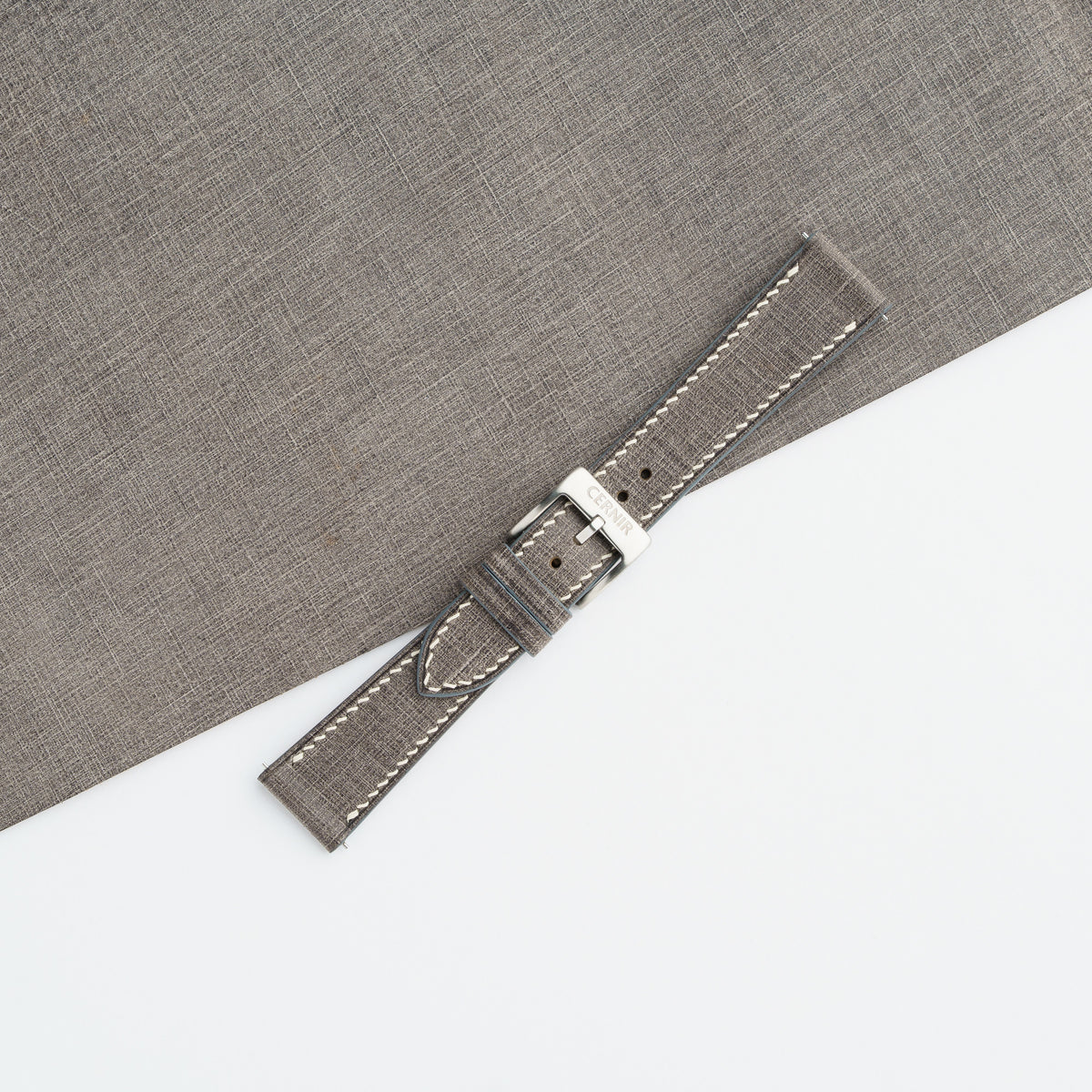 Grey Babele slim watch strap buckled in a loop, showing the fine crosshatched surface