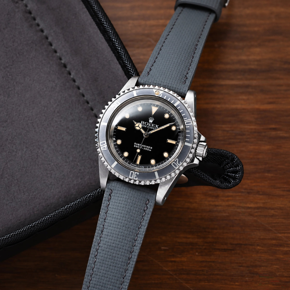 Grey sailcloth padded watch strap on a vintage Rolex Submariner beside a black zip case