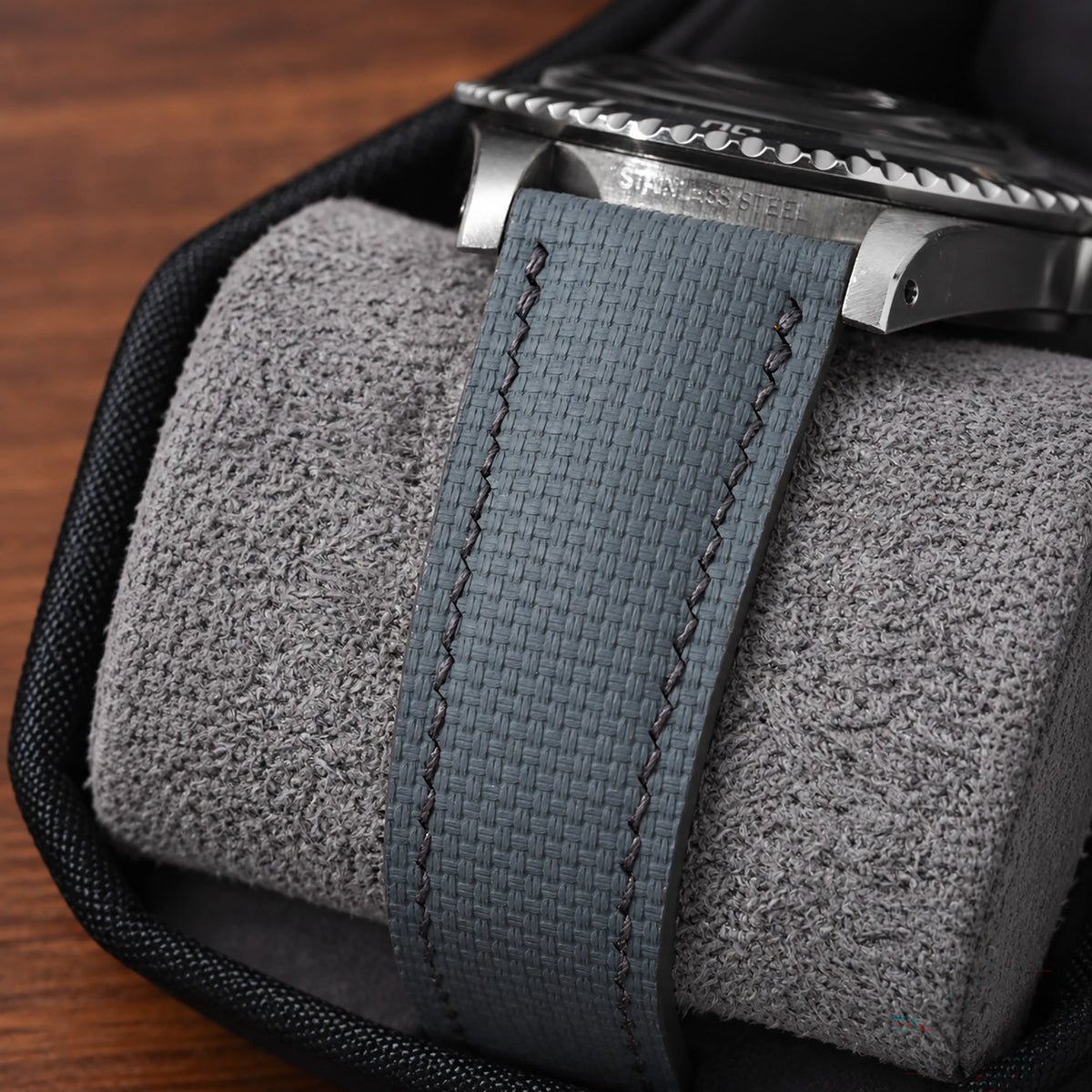 Close-up of the grey sailcloth padded strap on a steel diver resting on a watch cushion