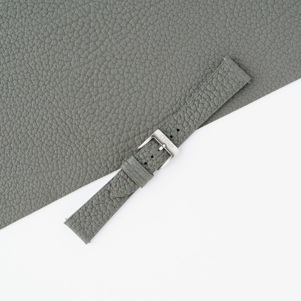 Grey Togo slim watch strap fastened with a steel buckle, showing the large pebbled grain