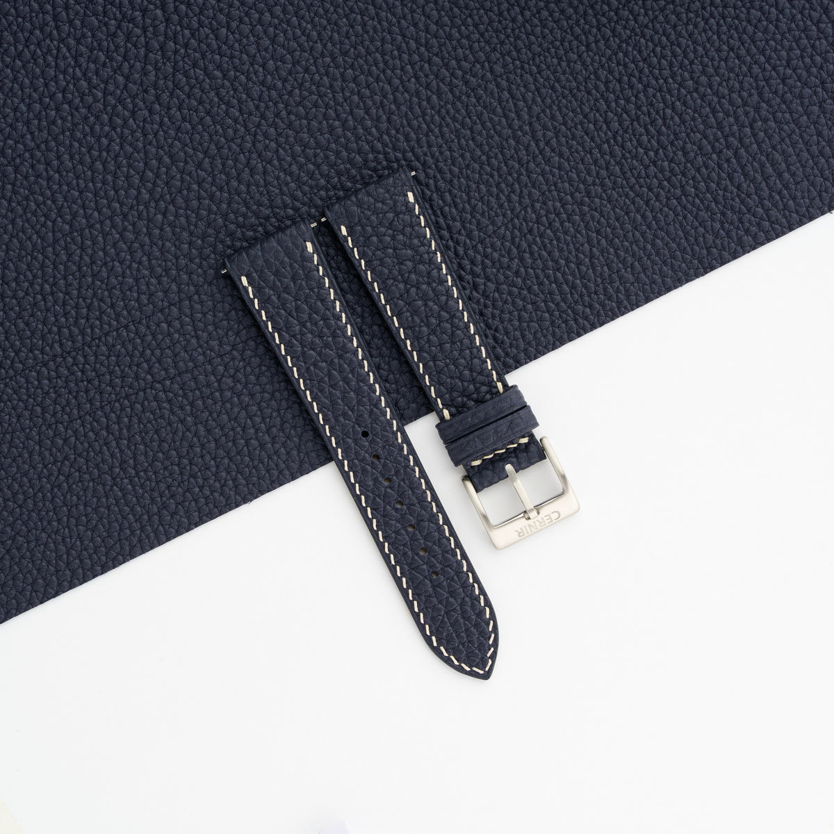 Navy blue Togo slim watch strap laid on a sheet of matching navy leather