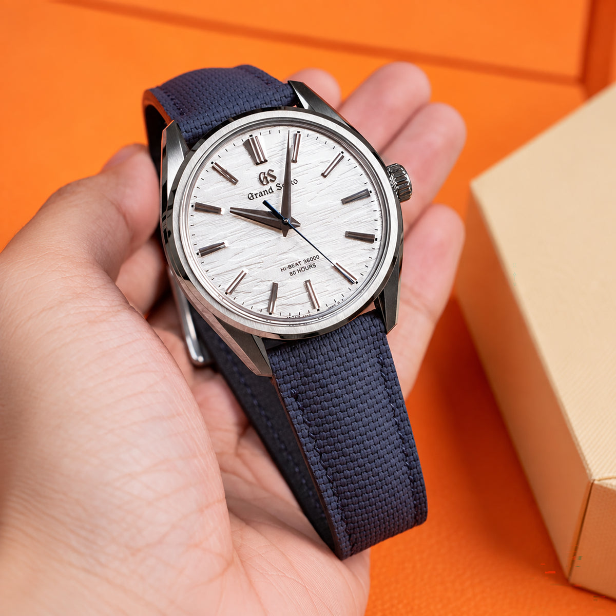 Navy rubber sailcloth padded watch strap on a Grand Seiko with a white textured dial