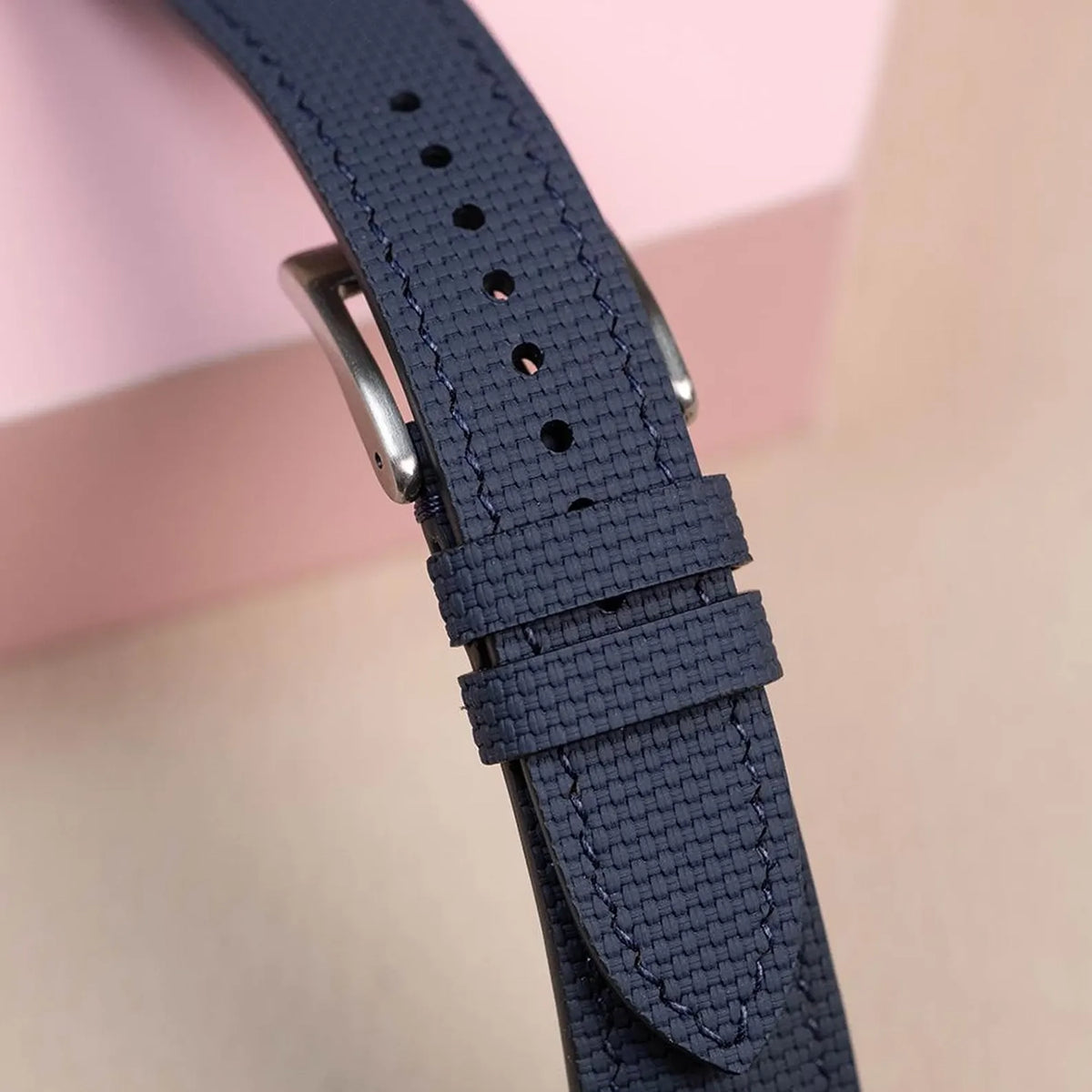 Close-up of the navy rubber sailcloth padded strap showing the sailcloth pattern, keepers and steel buckle