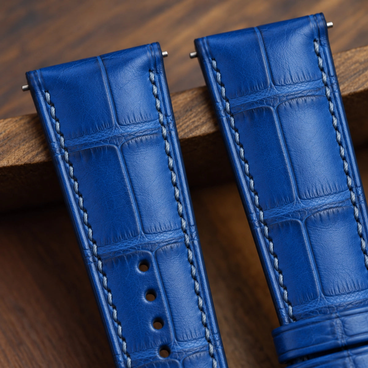 Close-up of the ocean blue alligator padded strap showing square scales and matching stitching