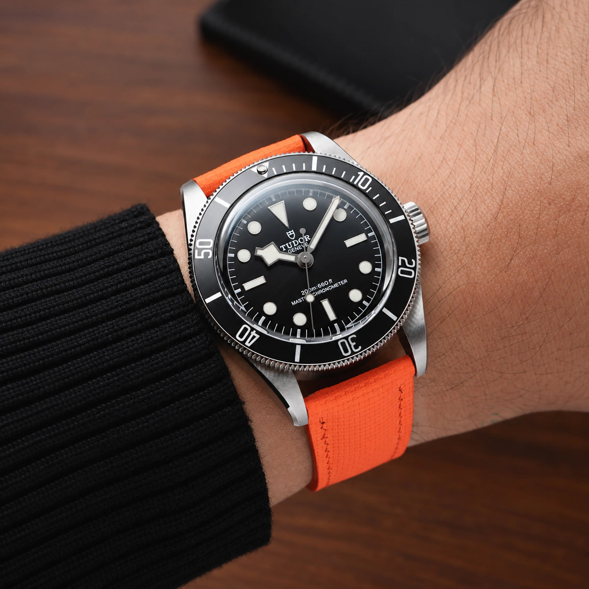Orange sailcloth padded watch strap worn with a Tudor dive watch with a black dial