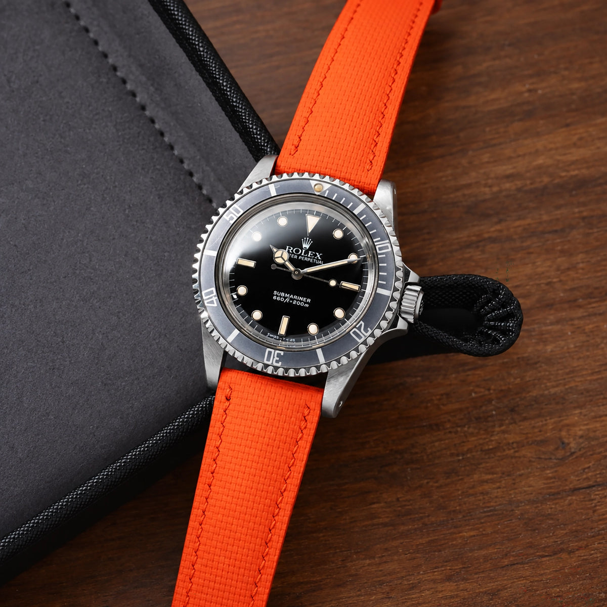 Orange sailcloth padded watch strap fitted to a vintage Rolex Submariner on dark wood