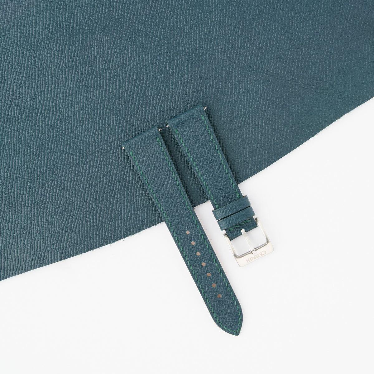 Petrol blue Epsom slim watch strap laid on a sheet of matching petrol blue Epsom leather