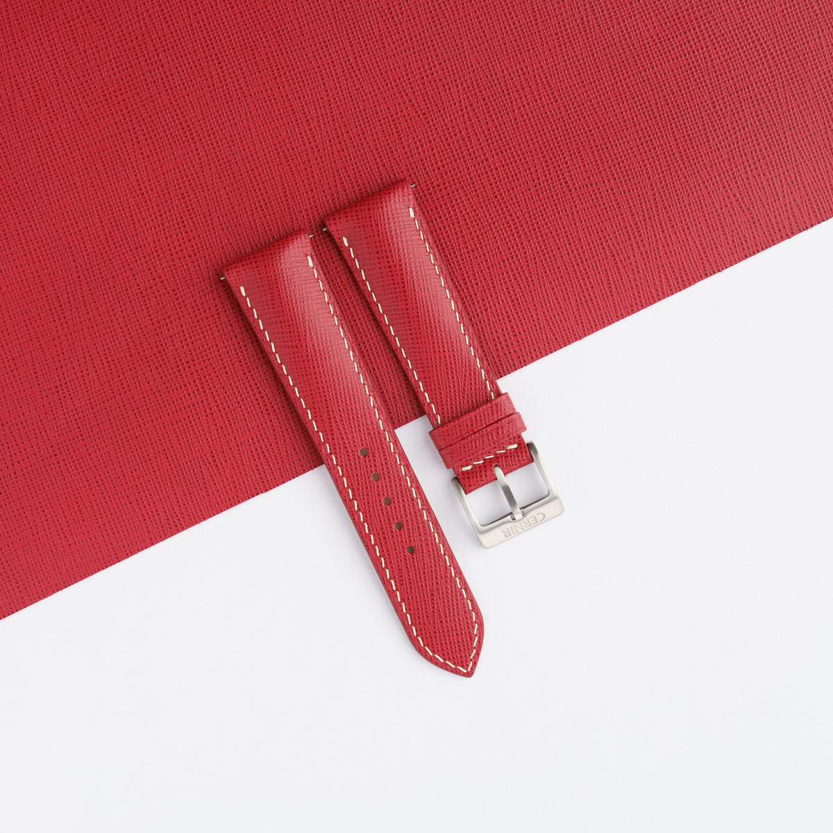 Red Saffiano padded watch strap laid on a sheet of matching red Saffiano leather