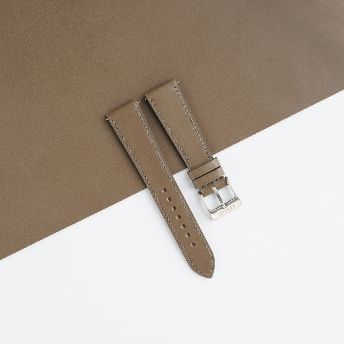 Taupe Buttero slim watch strap laid on a sheet of matching taupe leather
