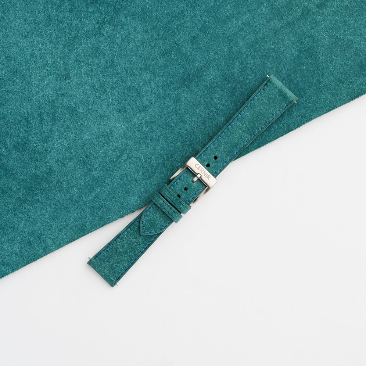 Buckled turquoise Pueblo leather slim watch strap resting diagonally on turquoise leather