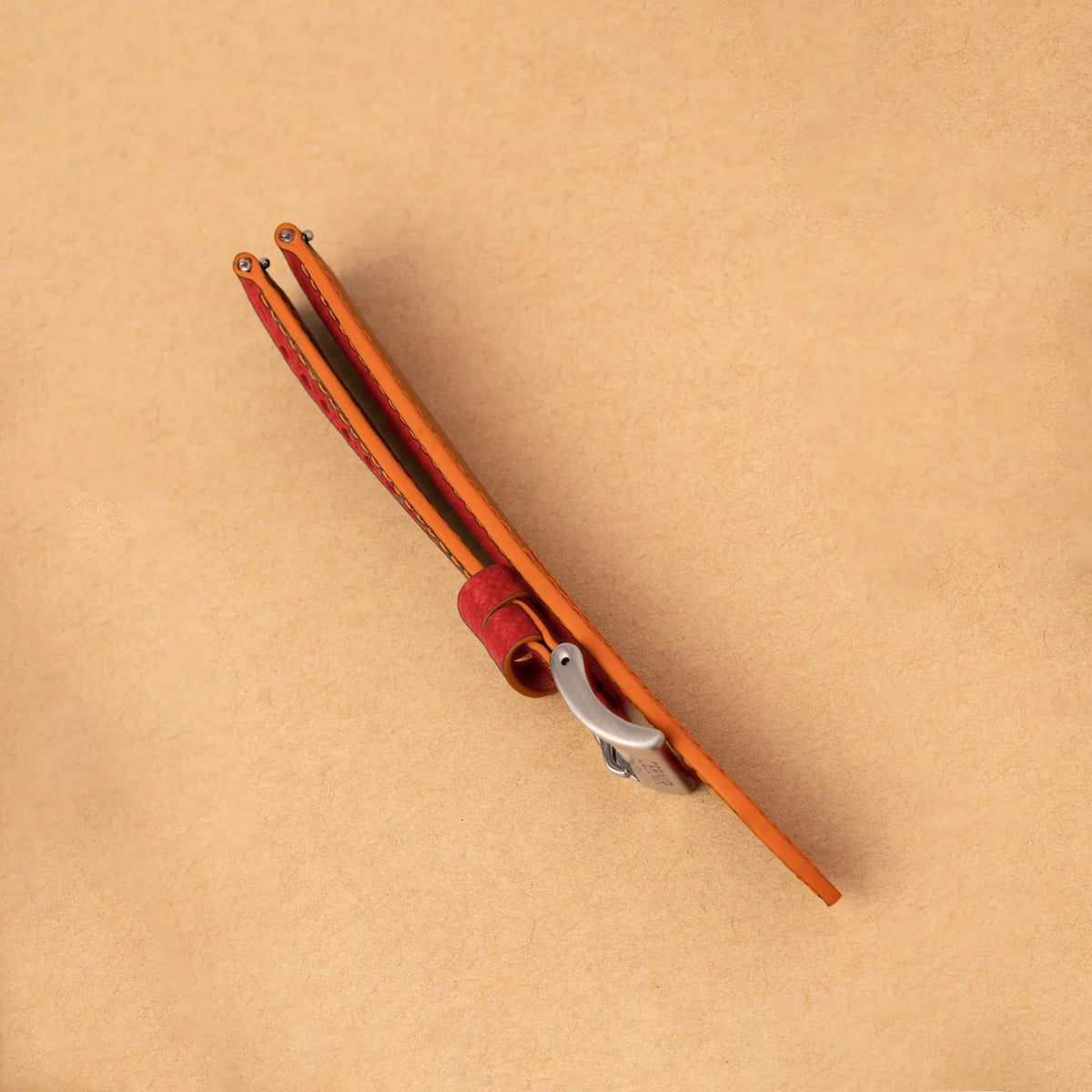 Side view of the padded coral red Epsom Racing Rally strap, showing its orange painted edges
