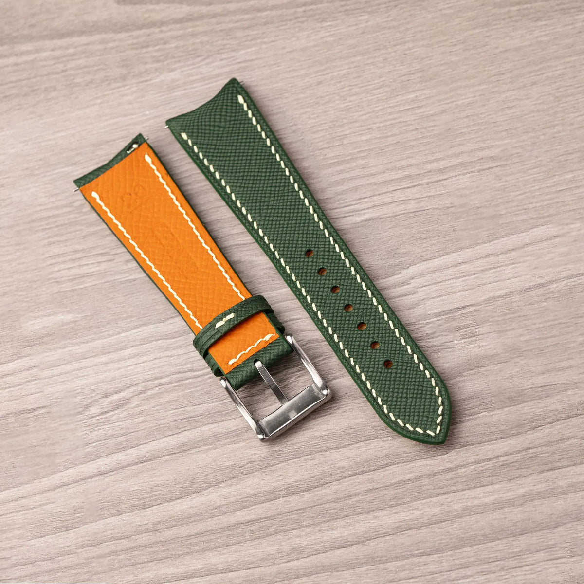 Orange Epsom lining with the Cernir stamp on the back of the forest green Saffiano curved end strap