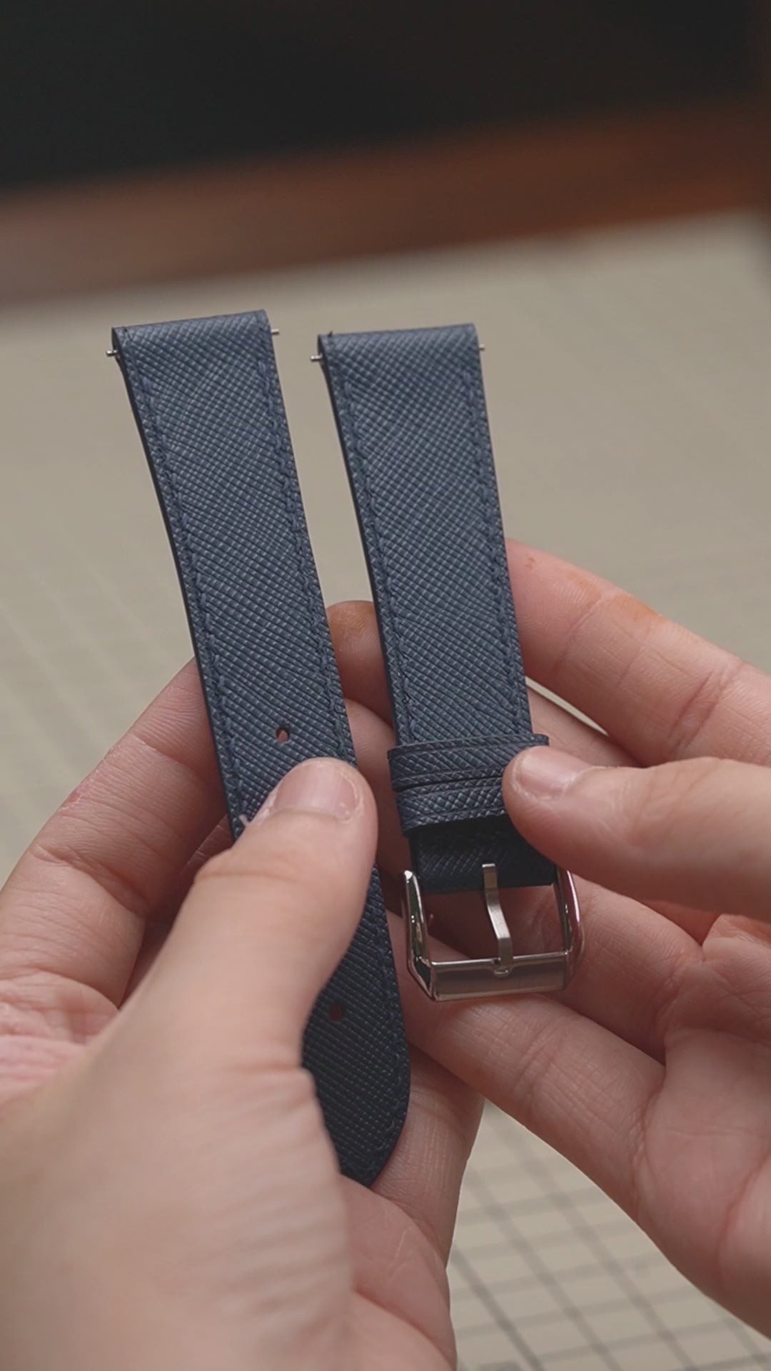 Video: Denim Blue Saffiano Leather Slim Watch Strap held in both hands, showing both pieces and the buckle