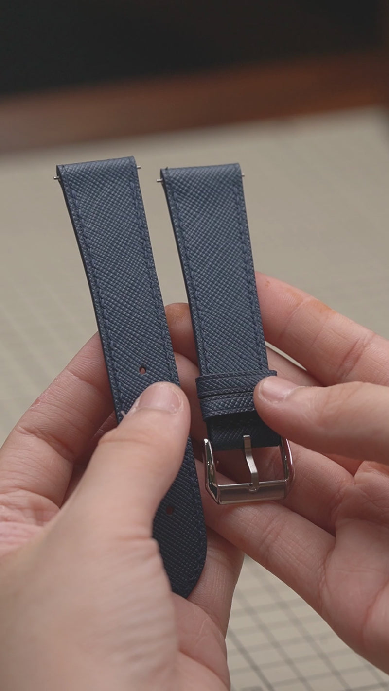 Video: Denim Blue Saffiano Leather Slim Watch Strap held in both hands, showing both pieces and the buckle