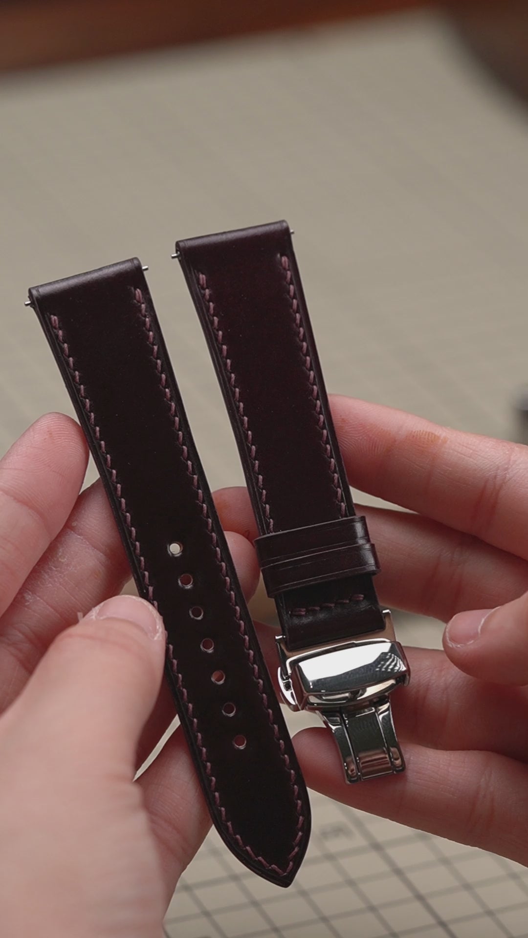 Video: Burgundy Shell Cordovan Leather Slim Watch Strap with a folding clasp, held in both hands